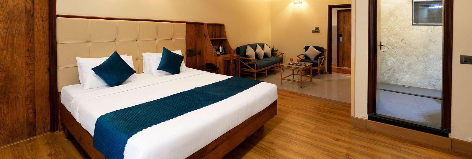 An Executive Room with a queen size bed, a seating area, a bathroom, and stylish decor - Cross Roads Inn, Bengaluru