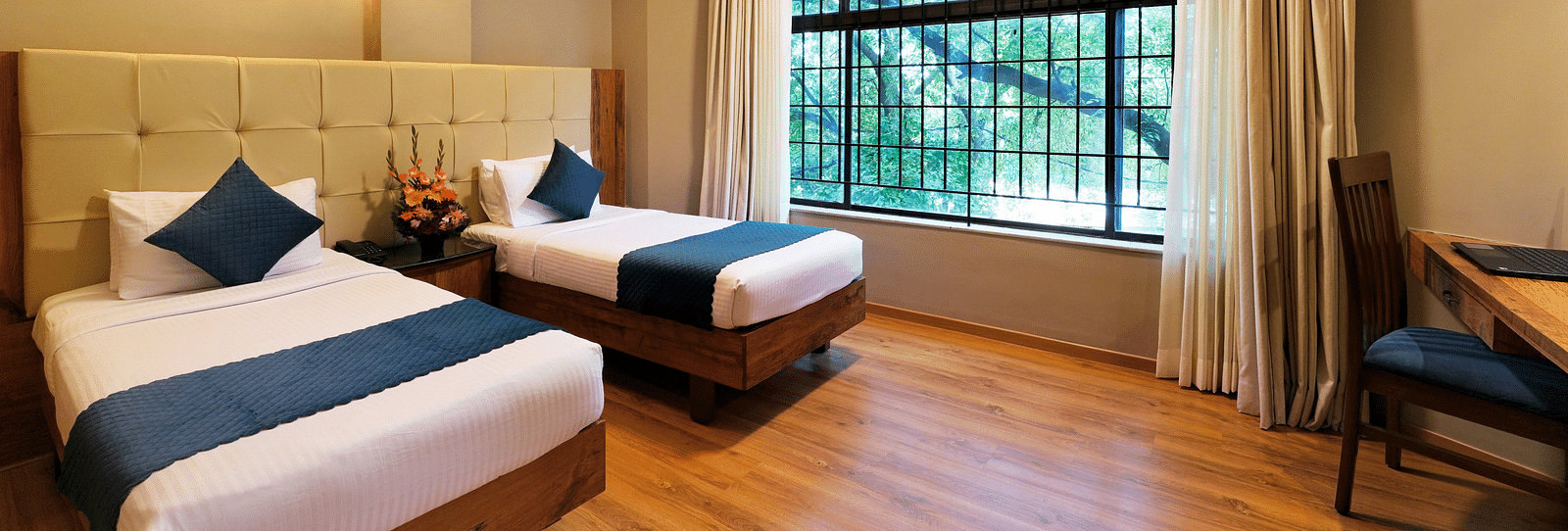 An image of our Deluxe Room featuring twin beds and a view from the window - Cross Roads Inn, Bengaluru
