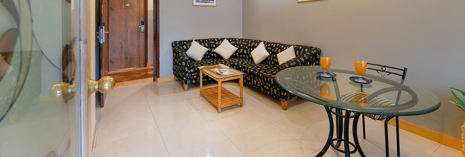 A seating area in our Suite in Bangalore with a glass table, a chair and a comfortable couch - Cross Roads Inn, Bengaluru
