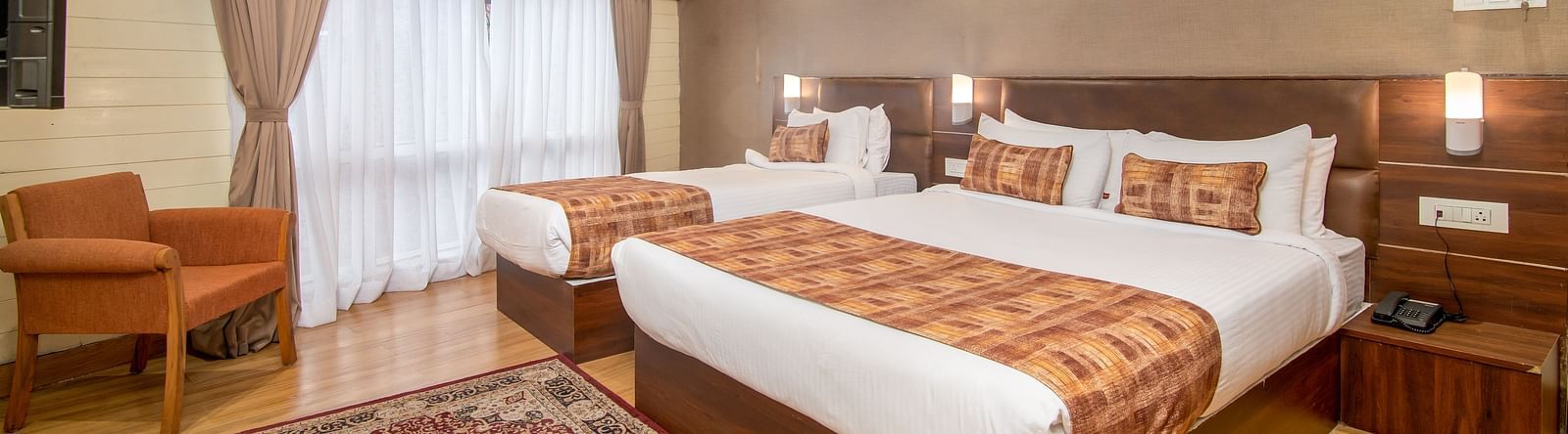 An image of a room with a queen size bed and a single bed with TV and minimal decoration - Sumitel Vista TV Tower