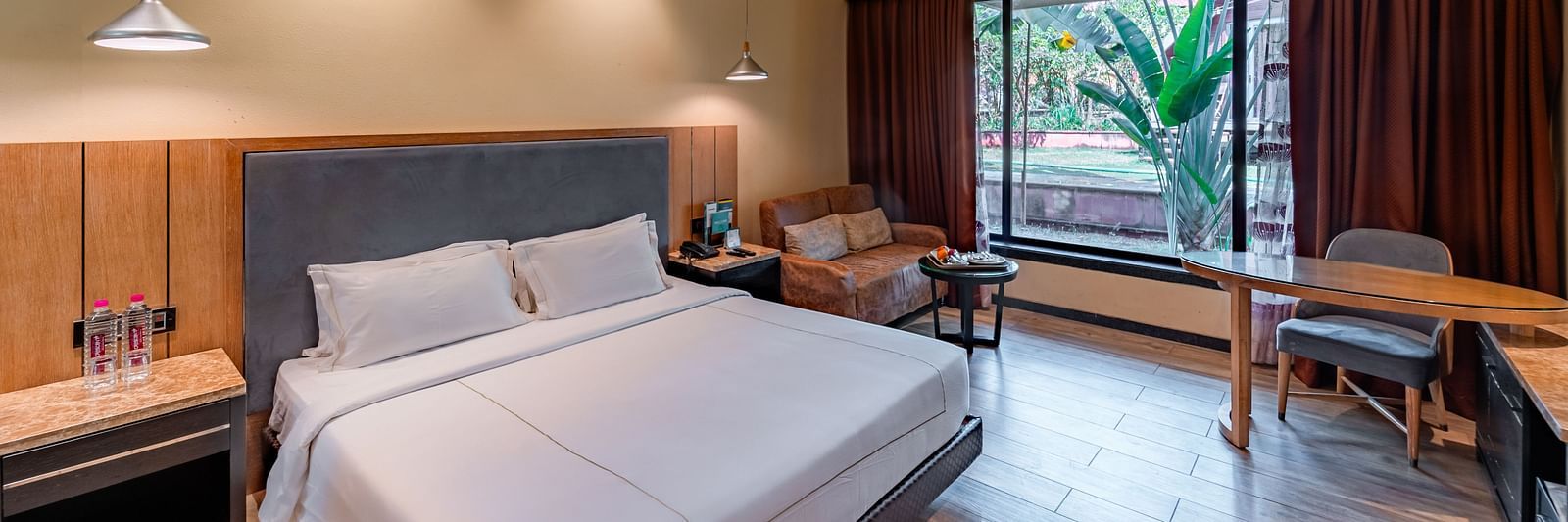 Club Room features a spacious bed, cushioned sofa, and a large window showcasing a natural view at Crescent Spa & Resort, Indore