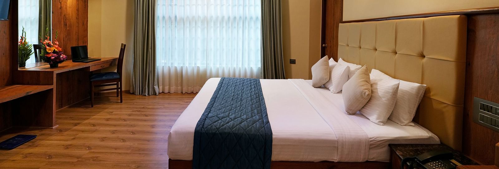 An Executive Room with a large bed, wooden decor, and natural light - Cross Roads Inn, Bengaluru