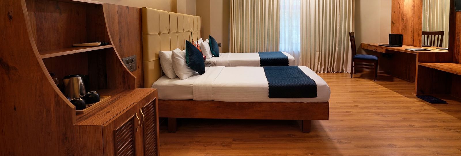 A spacious Executive Room with twin beds and a work desk - Cross Roads Inn, Bengaluru