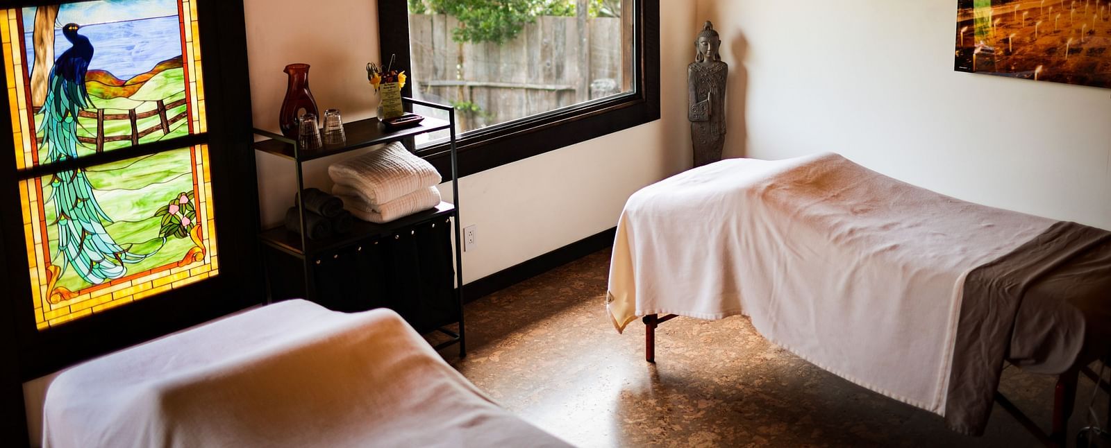 A massage room with soft lighting, white linens, and a window overlooking lush greenery - Brewery Gulch Inn & Spa