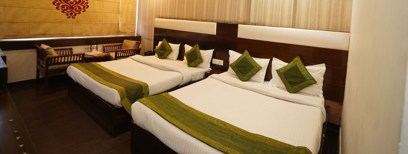 Spacious Family room at Hotel Dreamland, Chandigarh with King-size bed, two seating chairs with centre table, ceiling fan, AC with curtain rolled down.
