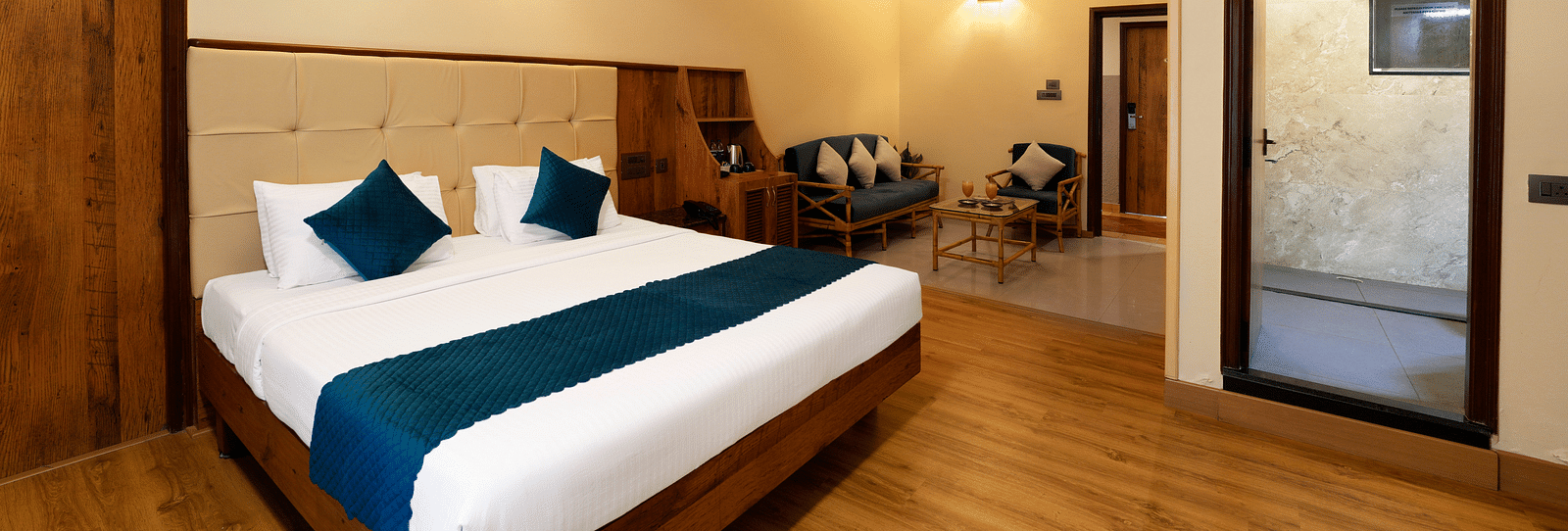 An Executive Room with a queen size bed, a seating area, a bathroom, and stylish decor - Cross Roads Inn, Bengaluru