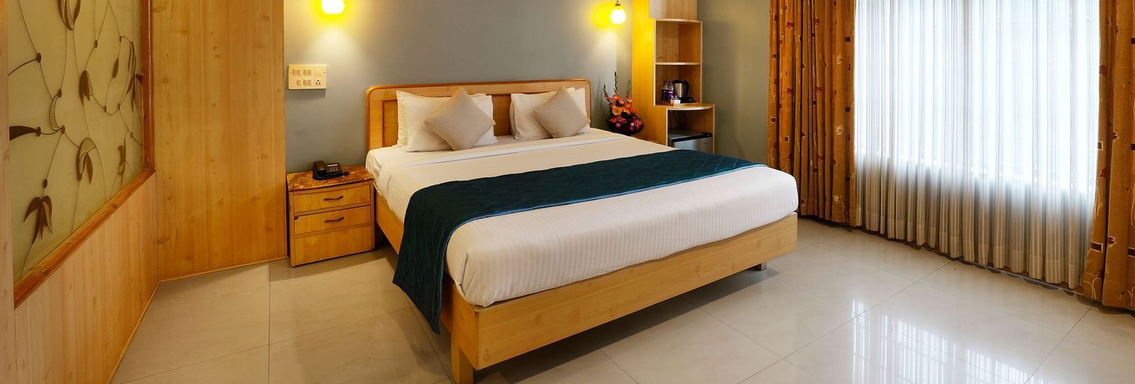 A spacious Suite with a king size bed and large windows - Cross Roads Inn, Bengaluru