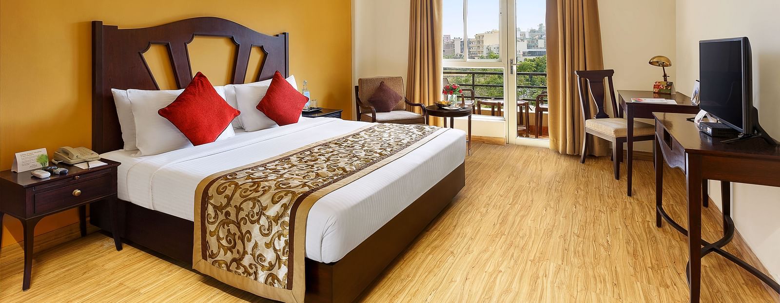 A side angle image of the room featuring a king size bed, coffee table and a large window enabling the outdoor view.