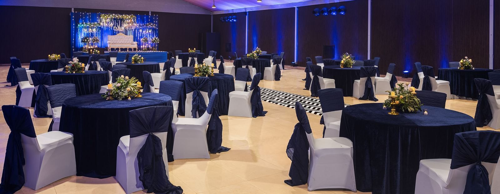 clusters of chairs and tables scattered across a room with chandeliers lighting up the hall - The Hideaway Banquets & Lawns, Greater Noida