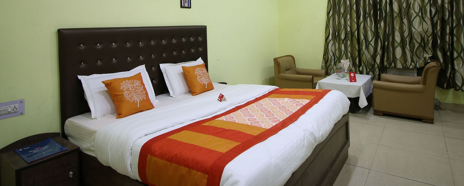 An image of our Family Suite in Roorkee with a large bed, a ceiling fan, two couches and a teapoy - Motel Divine International, Roorkee
