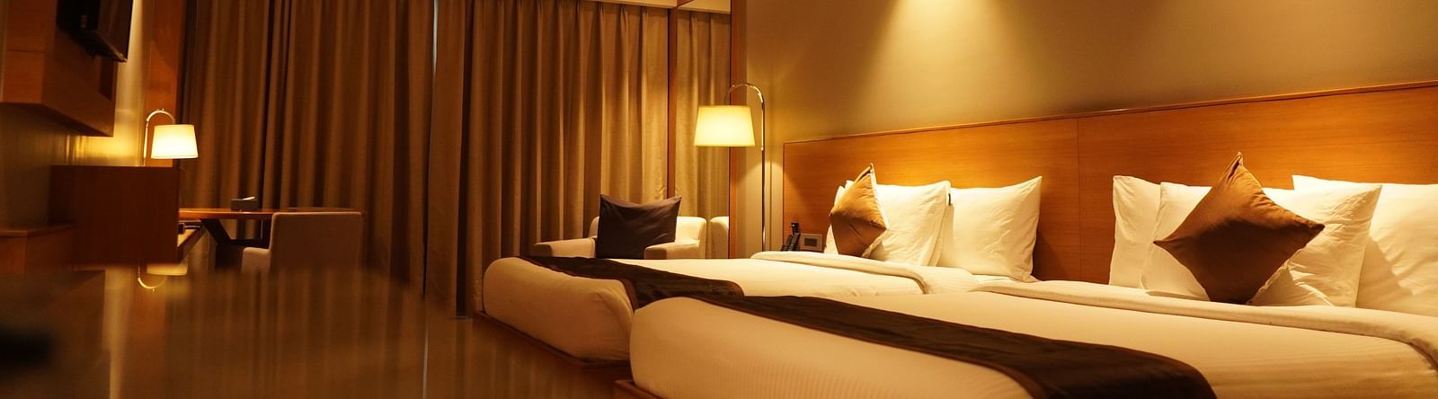 Two spacious beds with warm lighting and neatly made sheets