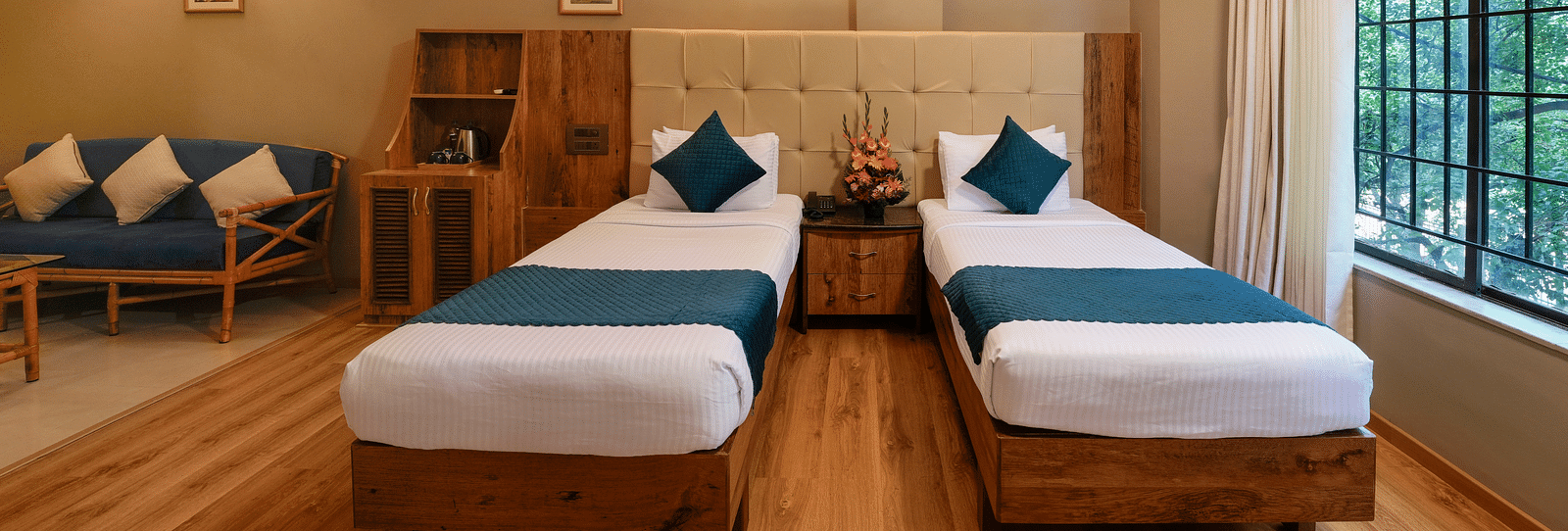 An image of a twin bed Deluxe Room with warm tones and modern amenities - Cross Roads Inn, Bengaluru