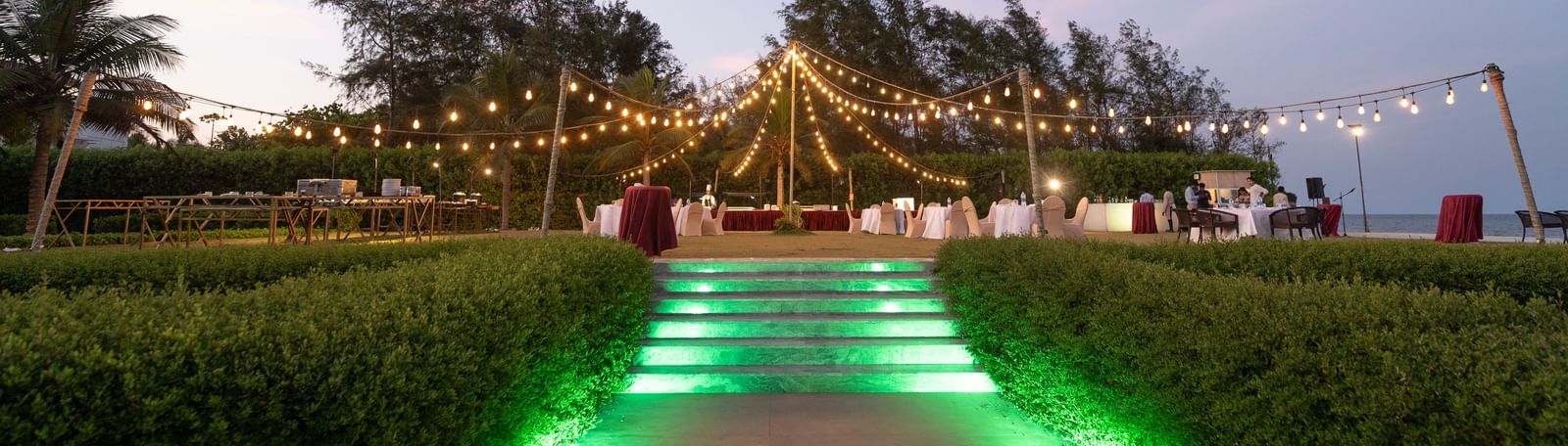 Garden pathway illuminated with green lights leading to an event area - Kaldan Samudra Palace