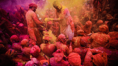 Group of people standing close together during Holi, covered in coloured powder and facing one another.