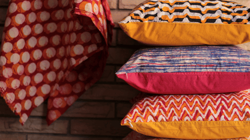 Pile of colourful patterned cushions and fabric on display.