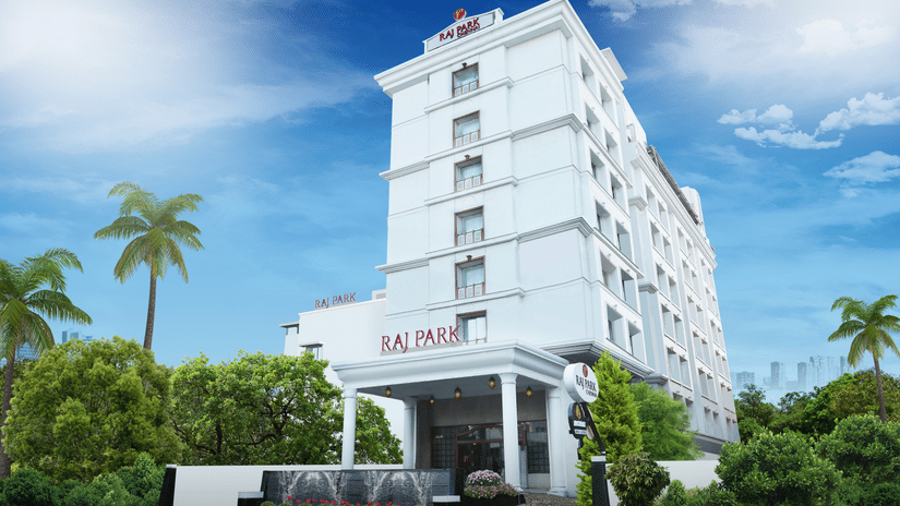 facade image of Raj Park Hotel, Chennai with trees on either side and blue sky in the background