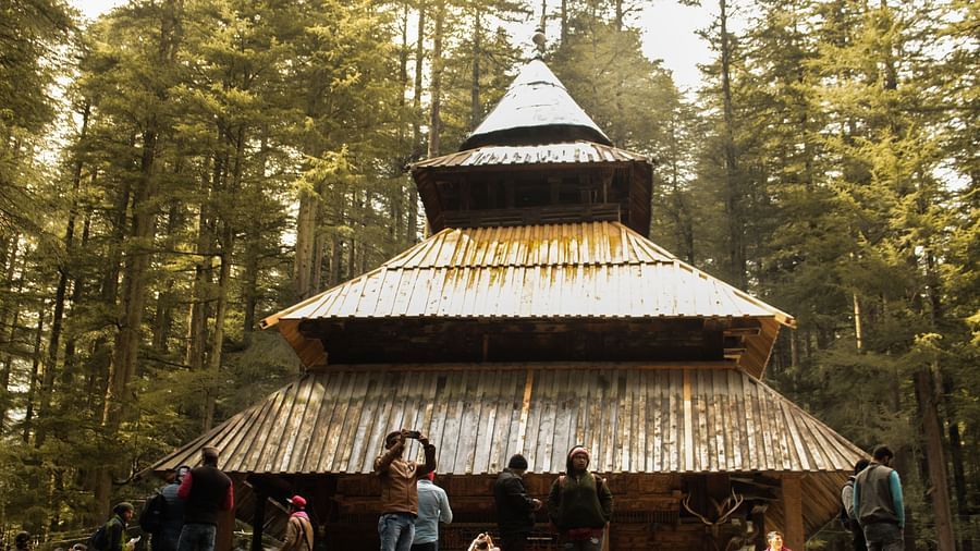 An image of people standing outside a temple with lush greenery around