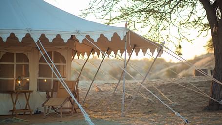 A spacious canvas tent with stylish frills, securely placed in the desert, stands ready for a luxurious escape in the golden light of dusk or dawn. - at Manvar Resort 