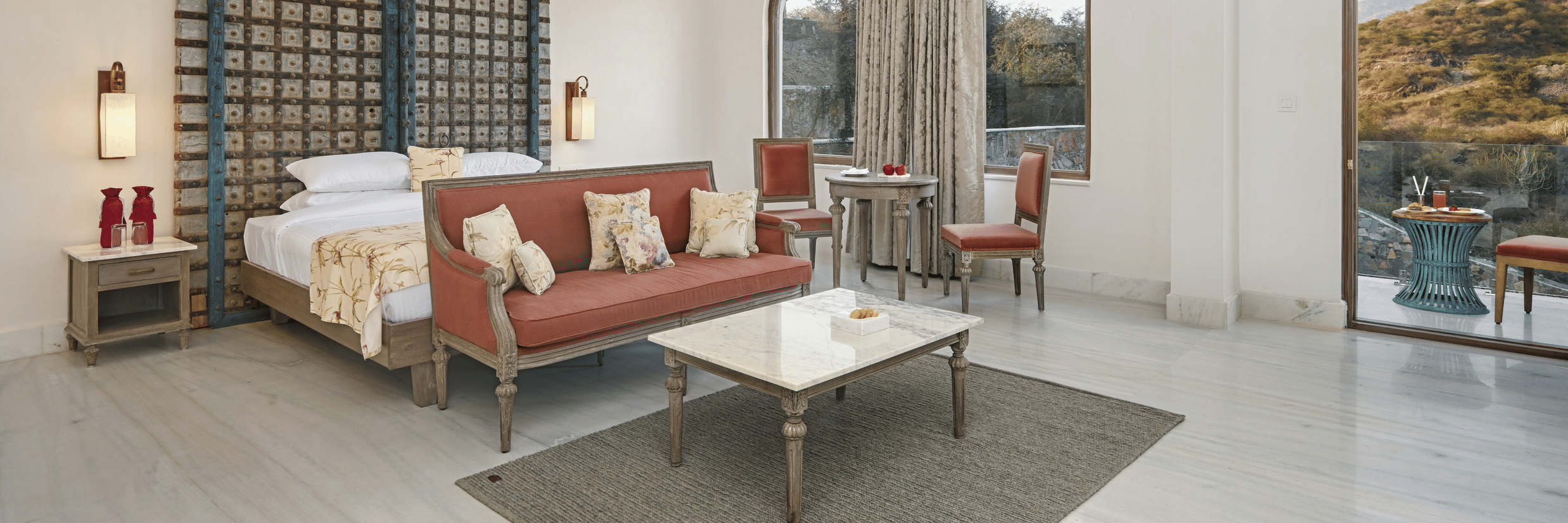 Interior view of the Fateh Vilas Suite, one of the best rooms in Udaipur at Fateh Vilas, featuring a king size bed, a sofa and a coffee table with balcony in view