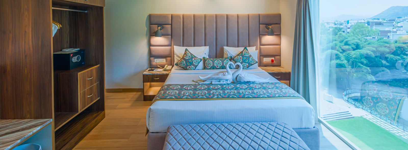 Sajjan Villa at Bamboo Saa Resort and Spa, Udaipur featuring a double size bed, a window with outdoor views, a small bed near the window, a wardrobe, and a ceiling fan.