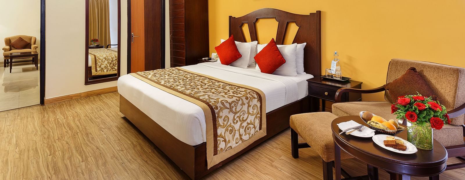 A side angle image of the room featuring a king size bed, coffee table and a wall painting hanging on the wall an d a TV.