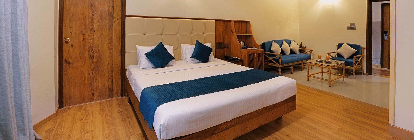 An Executive Room with a queen size bed, a couch, and a wooden decor - Cross Roads Inn, Bengaluru