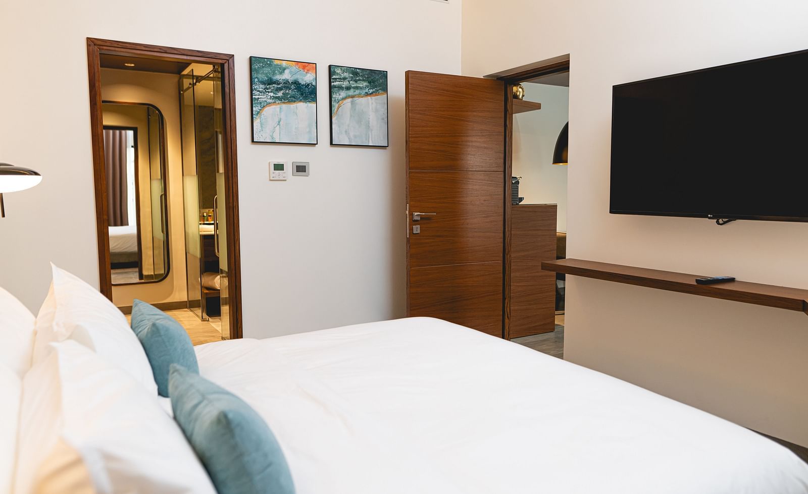 image of the bedroom with a wall mounted tv in the one bedroom suite of the kertel suites
