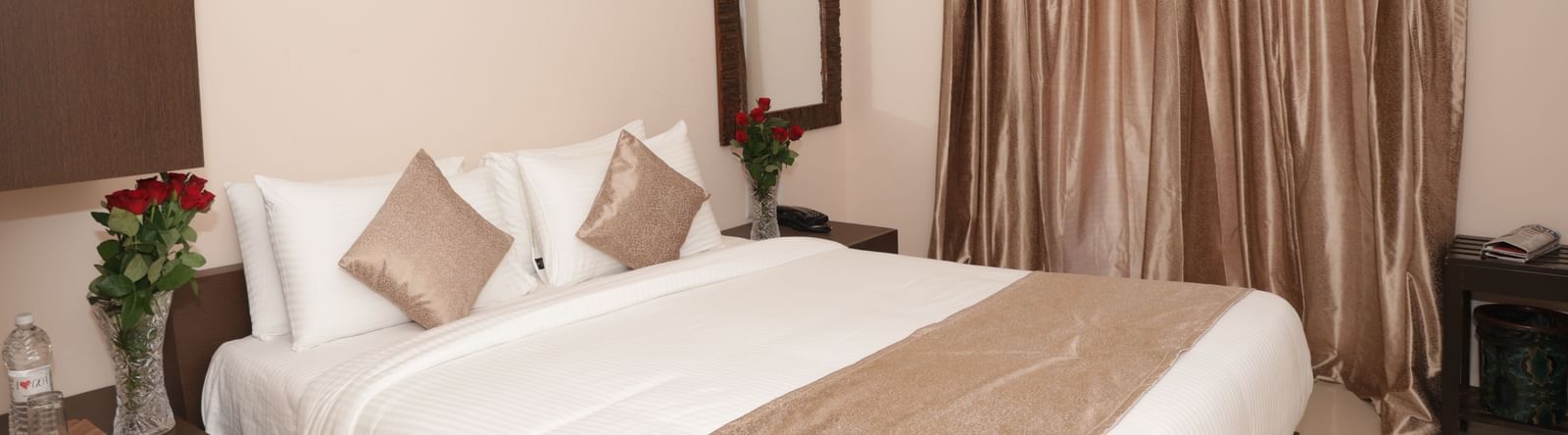A bed with pillows, bedside tables, flowers and window curtains at Nazri The Verda Hotel, Arambol.