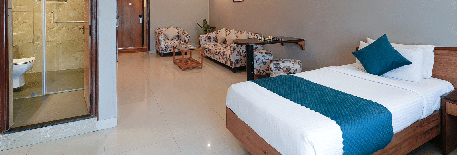  A hotel room in Bengaluru with a queen size bed, modern amenities, and a glass-partitioned bathroom - Cross Roads Inn, Bengaluru