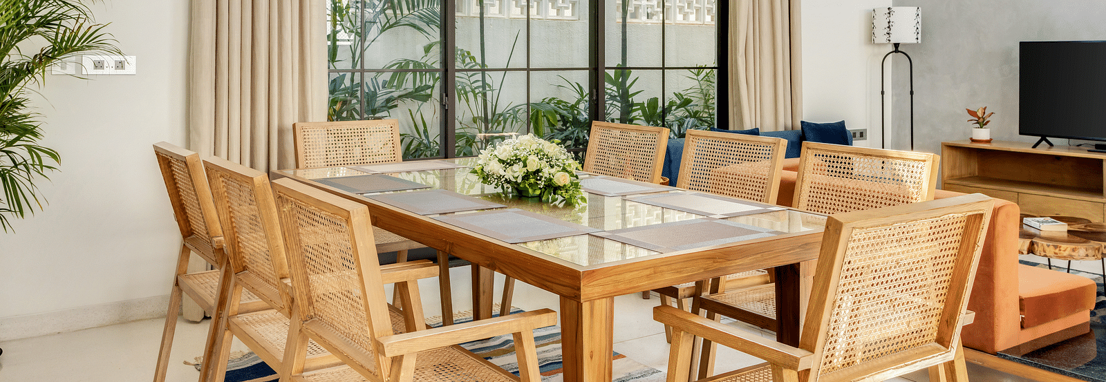 A dining area with a contemporary wooden table, modern chairs, and large windows bringing in natural light - BluSalzz Villas - Alocassia, Anjuna