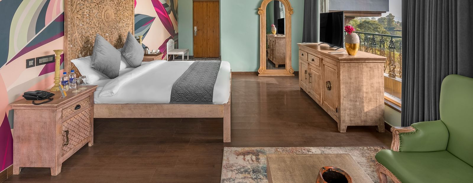 An image featuring a  bedroom with a comfortable bed, and a balcony. wooden flooring, wooden storage units - Atman, dharamshala