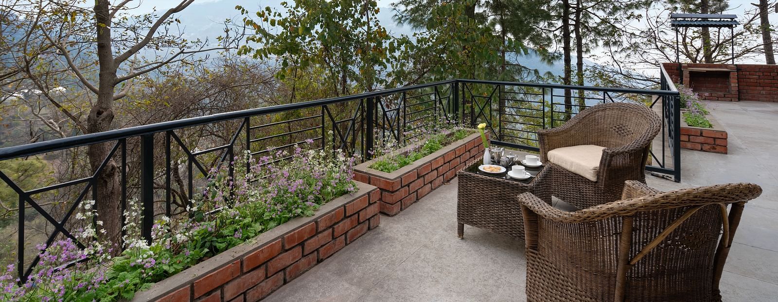 Two wooden chairs and a table set on an open balcony, inviting relaxation -  Baikunth resort, kasauli 