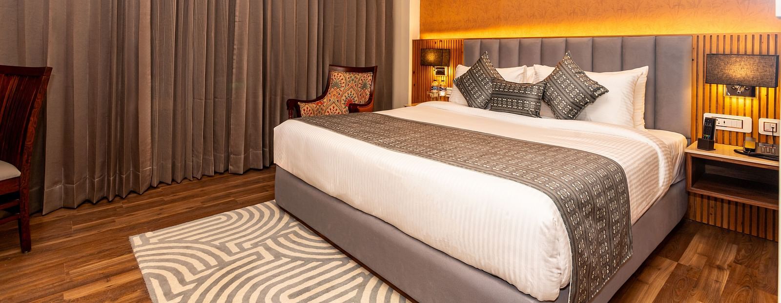 An image of a Deluxe Room with a bed, bed side table, lamps, and rug - The Belvedere Himalayan Retreat, McLeodganj