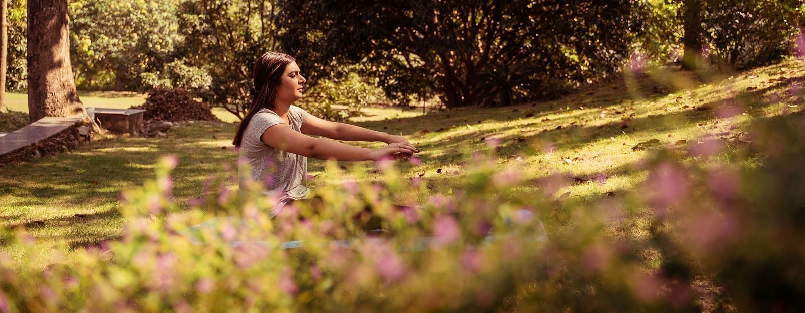 A woman practicing yoga surrounded by lush greenery at The Sylvan Retreat, Dehradun. 