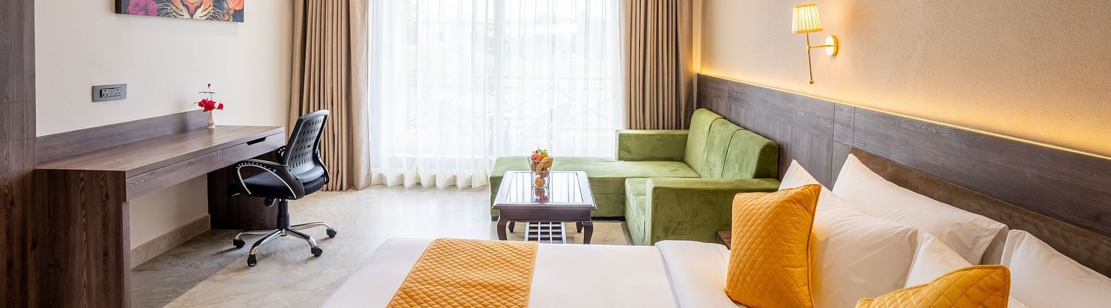 A image of the premium room with a large bed with a orange colour runner, a work desk and ambient lighting - Shervani Pebbles & Pines, Corbett