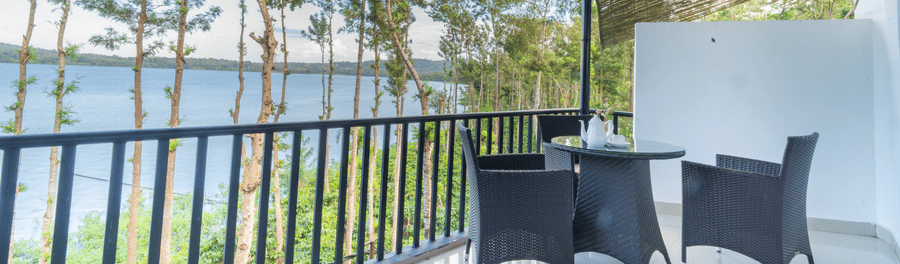 Image of a seating area with chairs and a table with a view of the nature around it at Coorg Jungle Camp Backwater Resort, Kushalnagar.