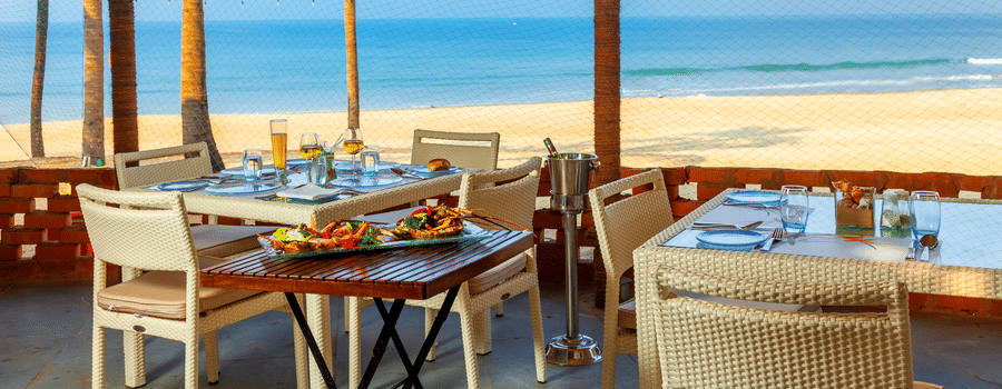 seating arrangements inside the shack with blue sky and beach in view - Caravela Beach Resort Goa.