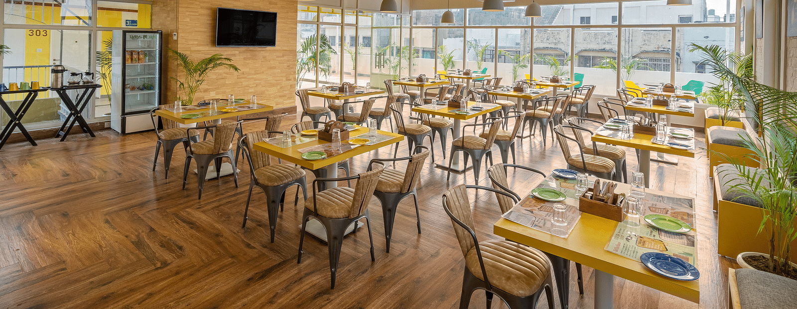 An image of a café interior featuring multiple tables set with menus and plates, chairs for dining.