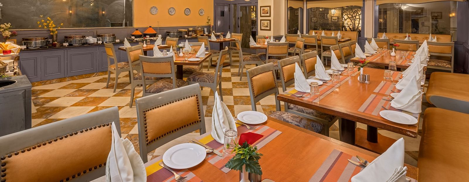 a view of a restaurant with a buffet setting and clusters of tables and chairs with lighting from four chandeliers - The Manor, Kashipur