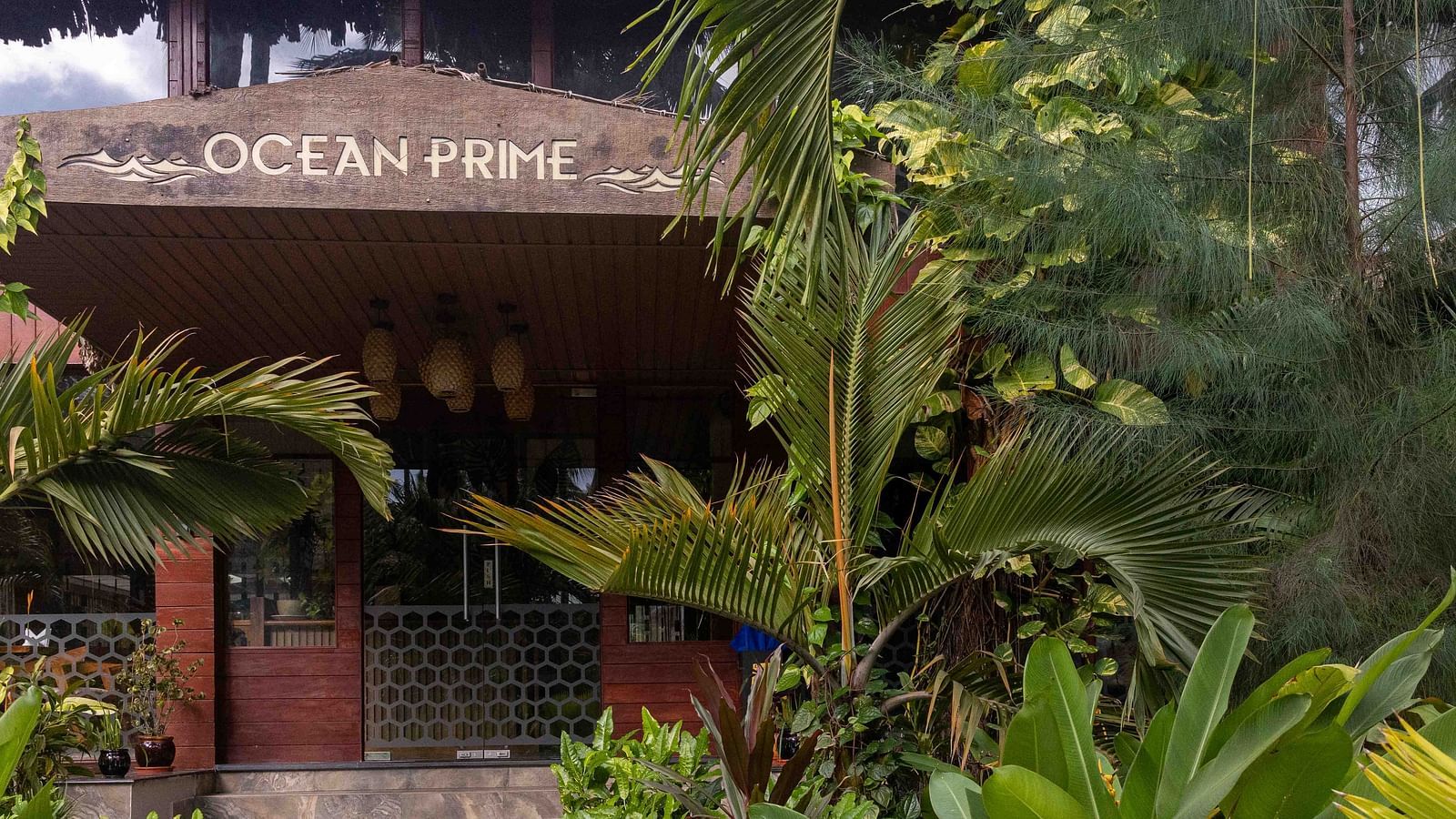 Facade of Ocean Prime at Coral Reef Resort & Spa in Havelock with a thatched roof, surrounded by lush greenery. The charming wooden structure gives the space a cosy and welcoming vibe - Coral Reef Resort & Spa, Havelock