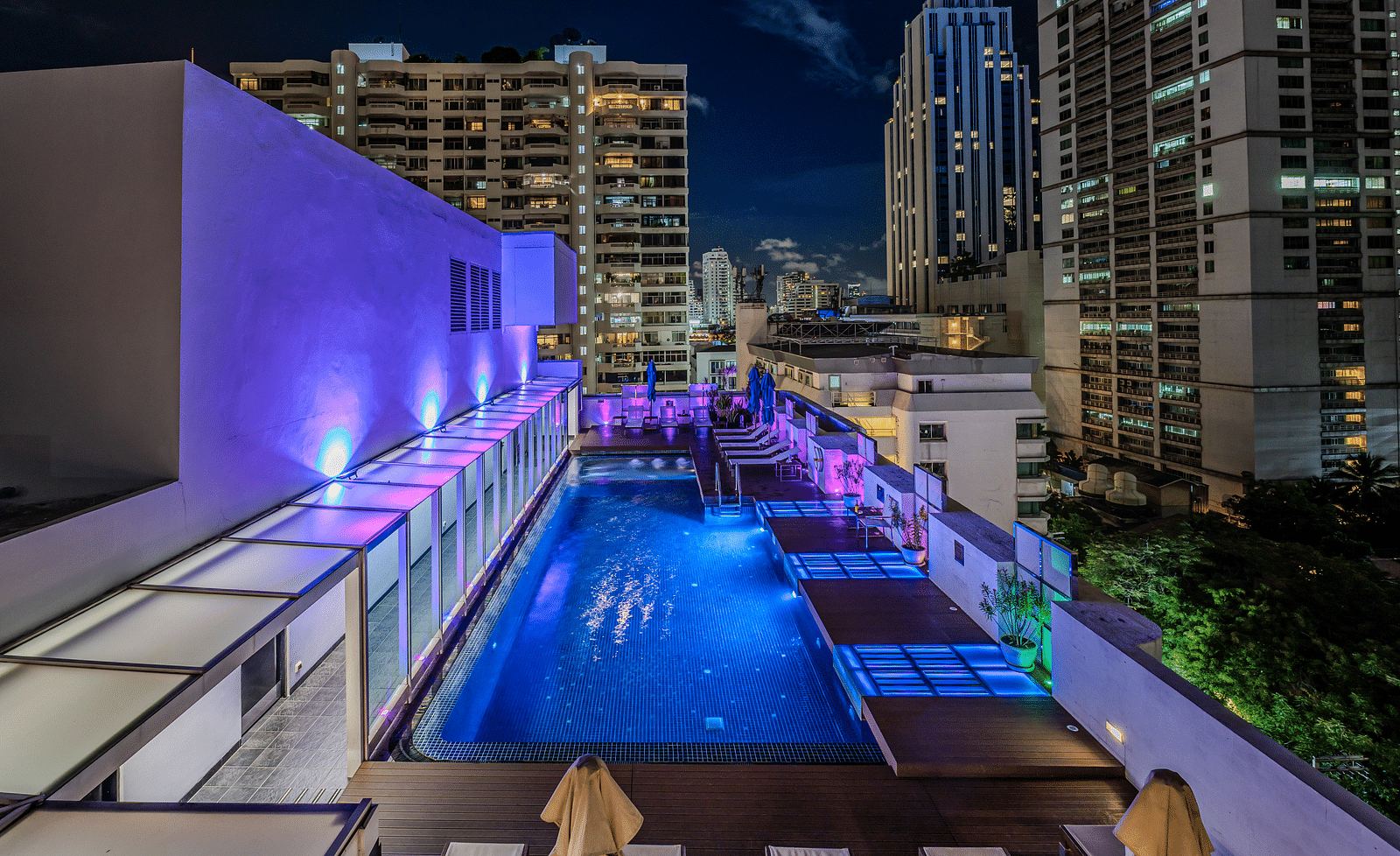 An overview of the rooftop swimming pool with the lights on  - Night Hotel Bangkok.