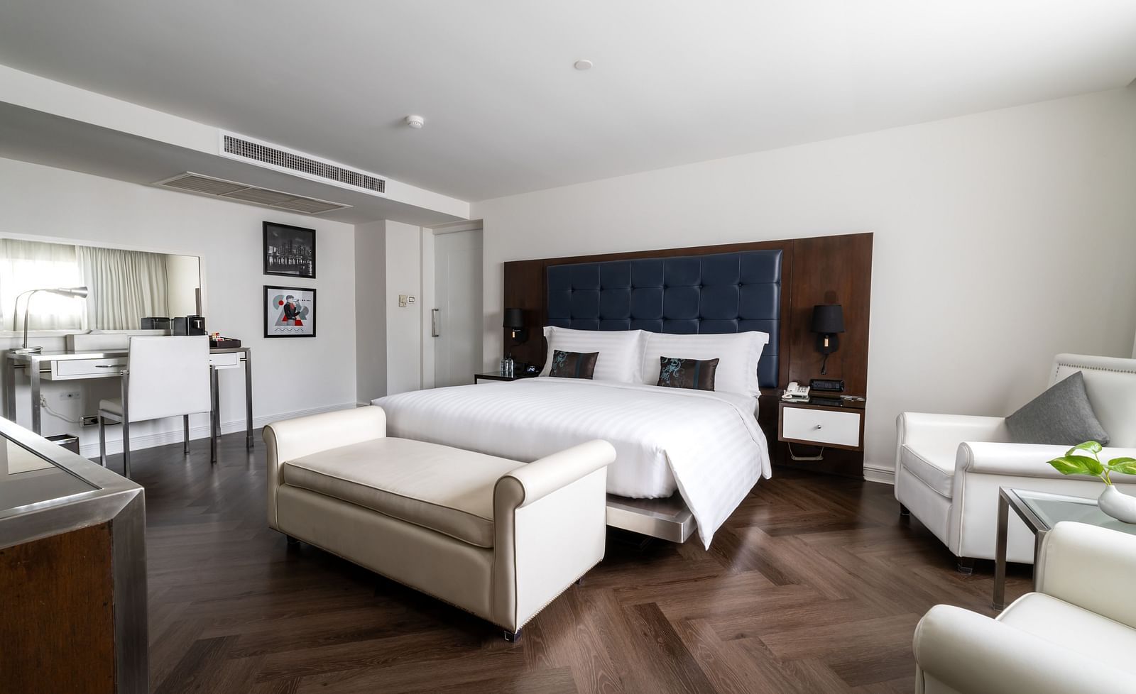 A king bed with a small sofa in front of it inside one of the rooms - Night Hotel Bangkok