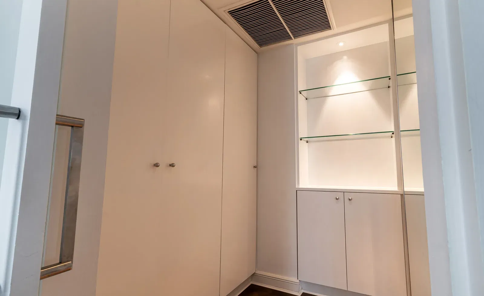 Walk-in wardrobe with white built-in closets and wooden shelving at Night Hotel Bangkok.