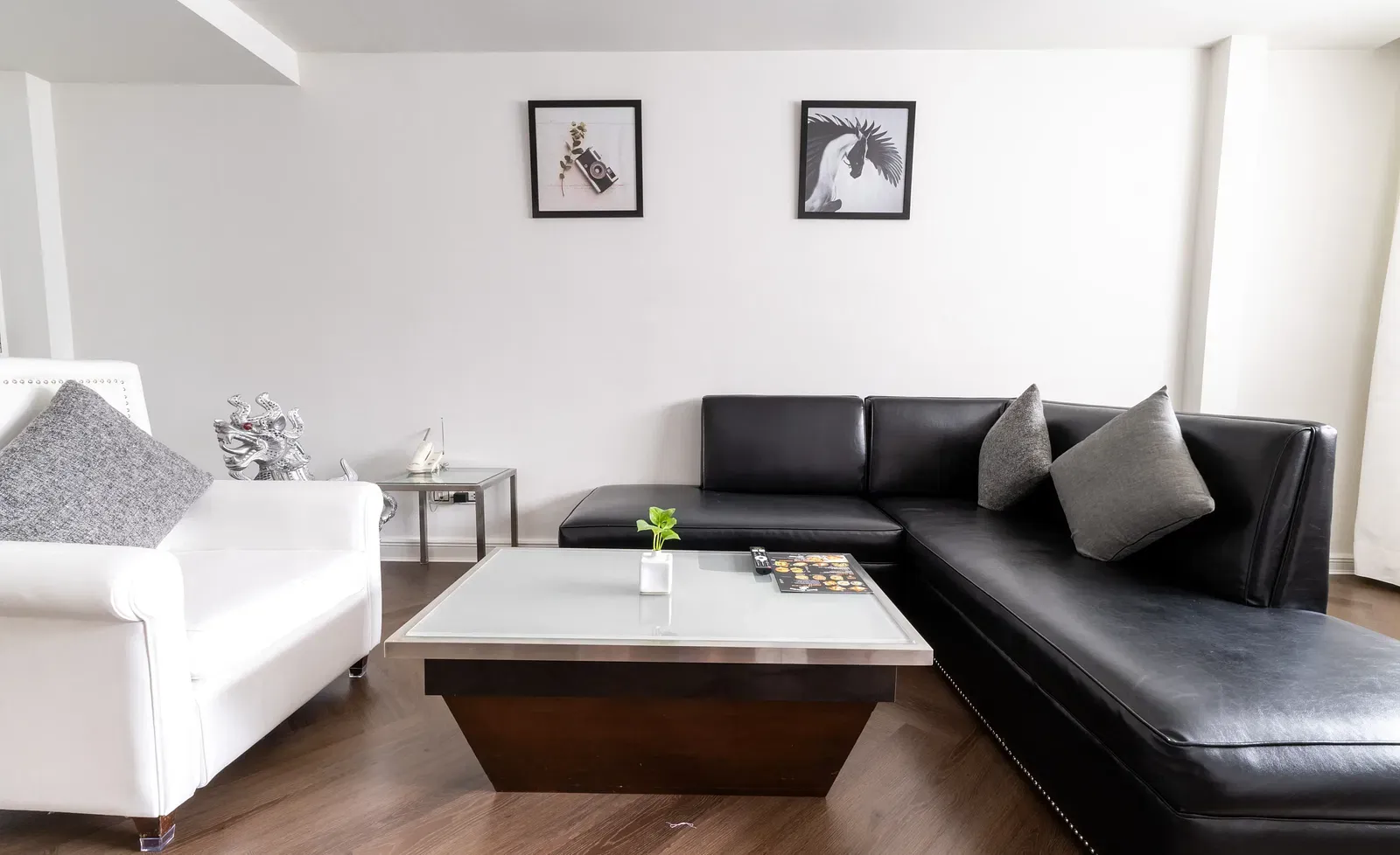 Spacious suite with L-shaped grey sofa, wooden coffee table, and white walls at Night Hotel Bangkok. 