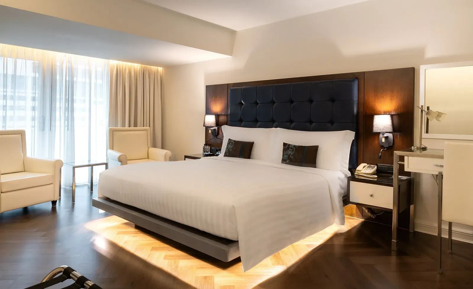 Luxury suite with platform bed, under-bed lighting, and lounge chair at Night Hotel Bangkok.