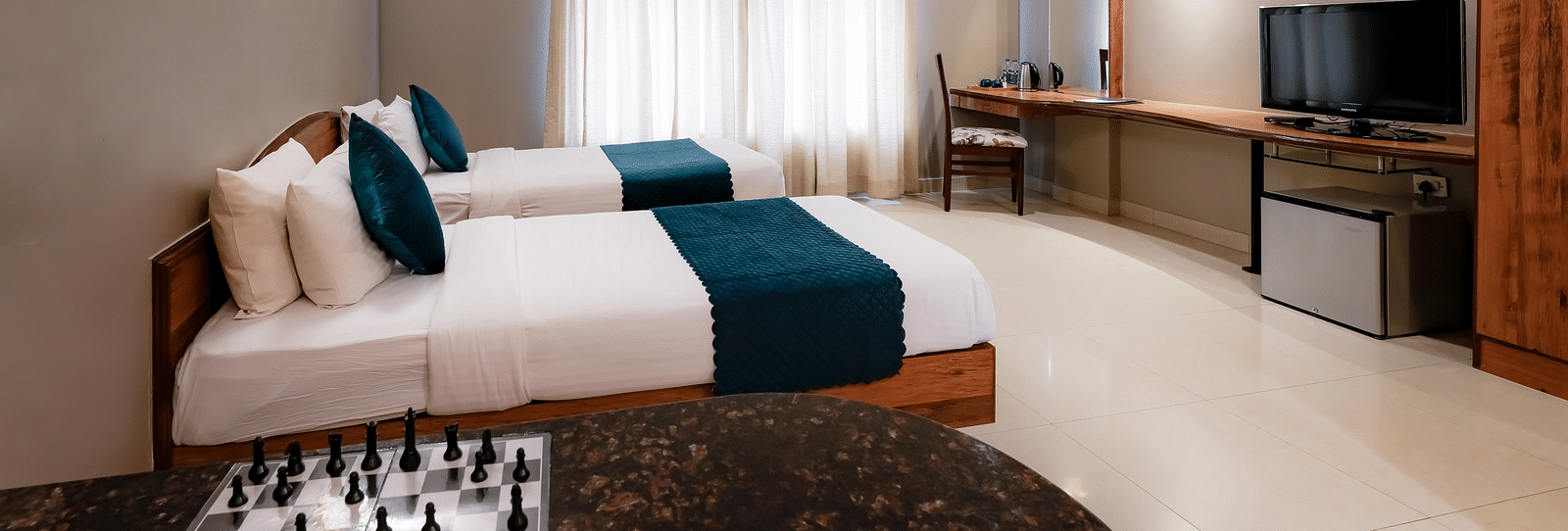 An Executive Room with twin beds, a desk with a chessboard, and stylish decor - Cross Roads Inn, Bengaluru