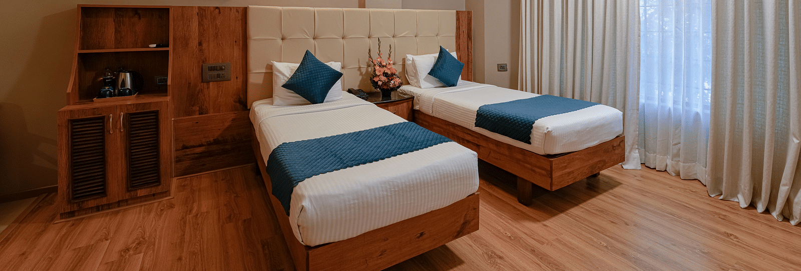 An image of our spacious Deluxe Room with twin beds and elegant lighting - Cross Roads Inn, Bengaluru
