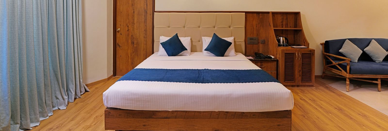 An image of a room with spacious layout, a queen size bed, a couch, and soft lighting - Cross Roads Inn, Bengaluru