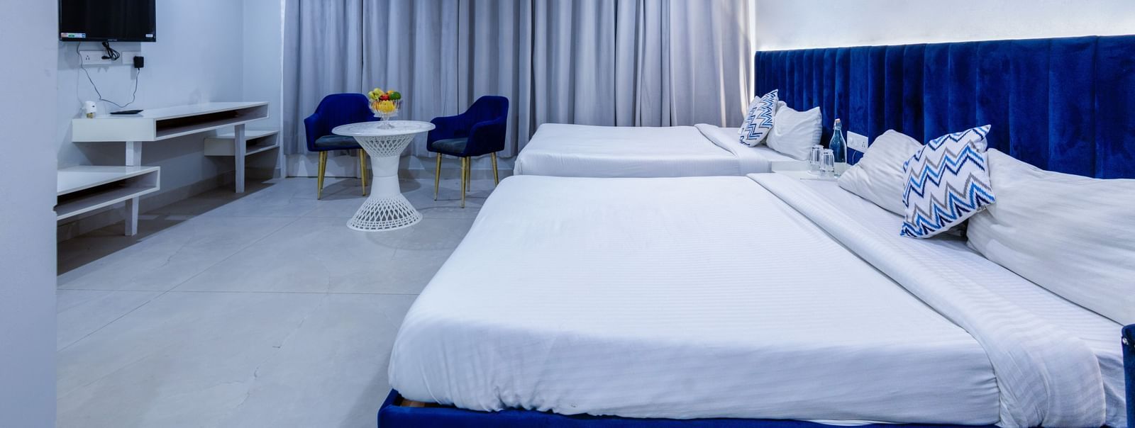 Family room bedroom with ambient lighting, sitting area, and floor-to-ceiling windows at Hotel Downtown17, Chandigarh.