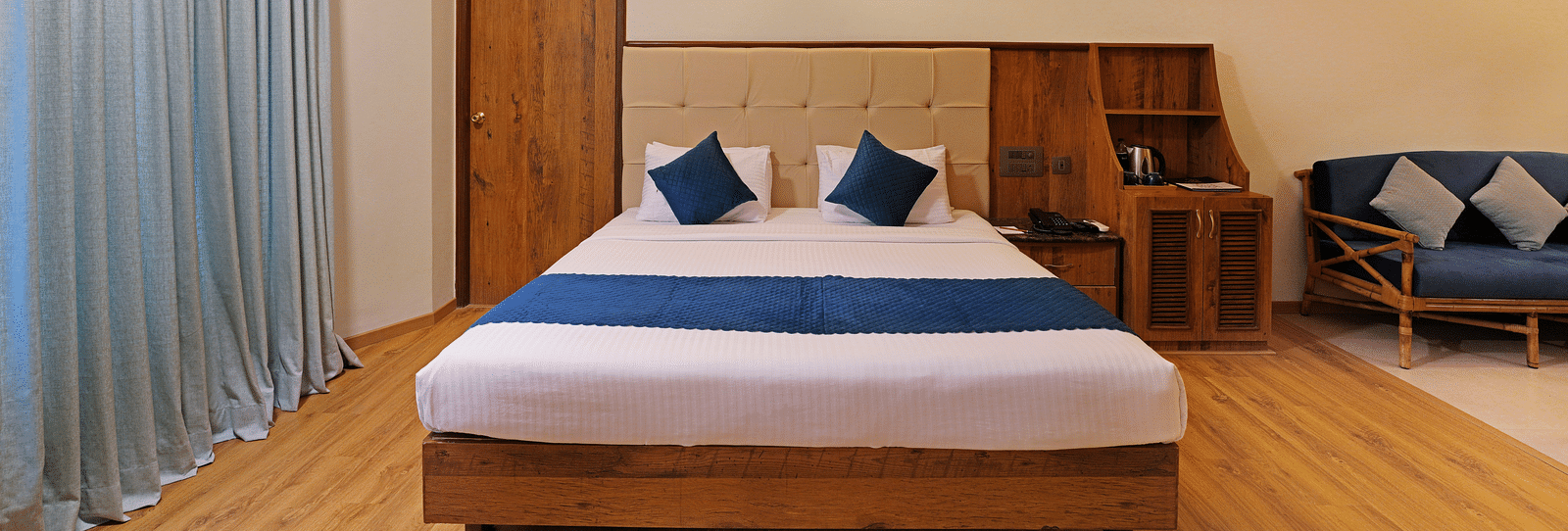 An image of a room with spacious layout, a queen size bed, a couch, and soft lighting - Cross Roads Inn, Bengaluru
